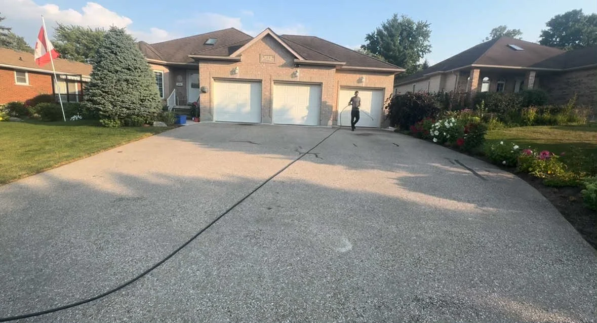 Freshly sealed asphalt driveway in front of a Kitchener-Waterloo home with a brick garage, after asphalt driveway sealing