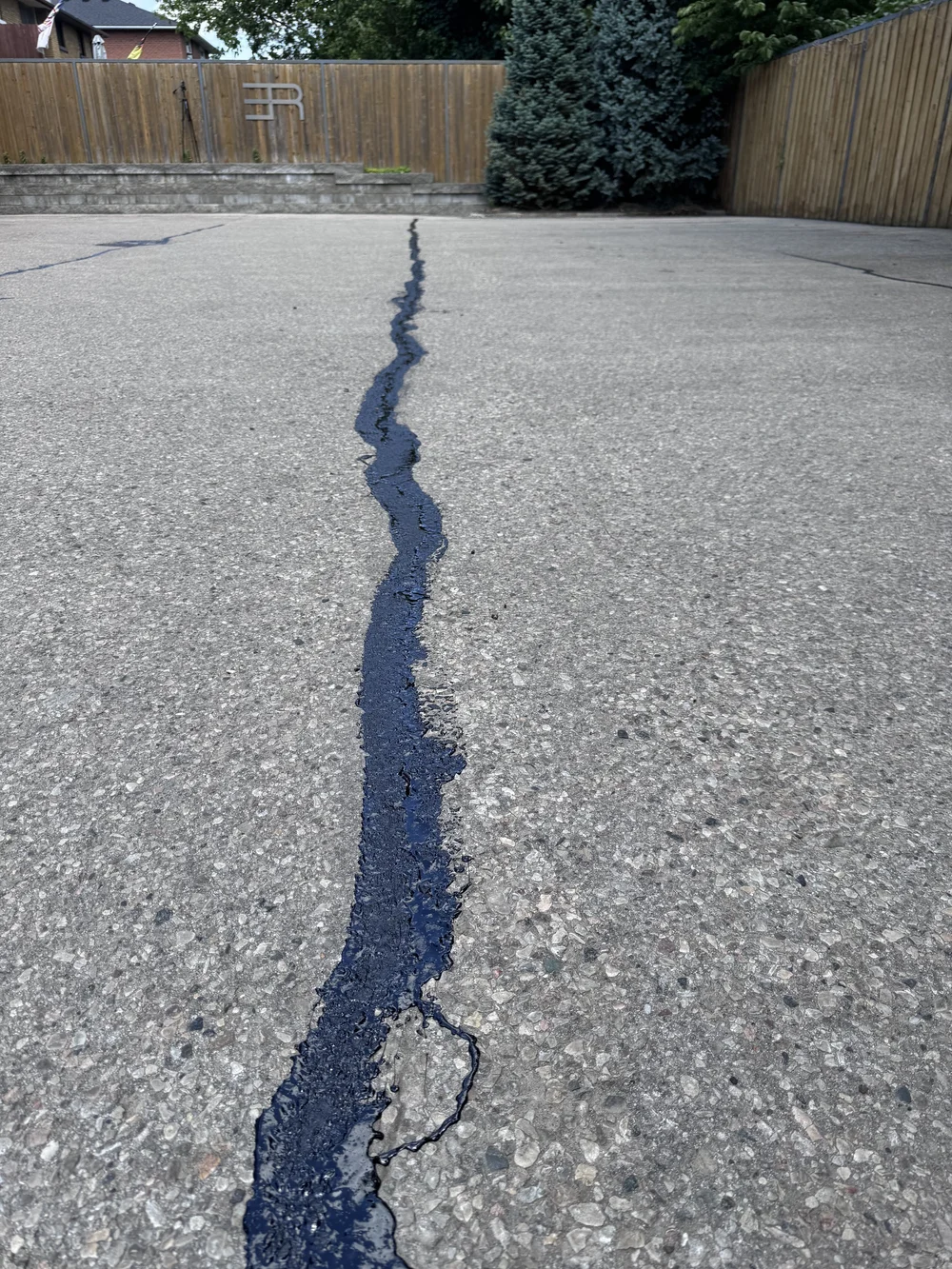 An image of asphalt hot rubber crack filler applied to a commercial parking lot
