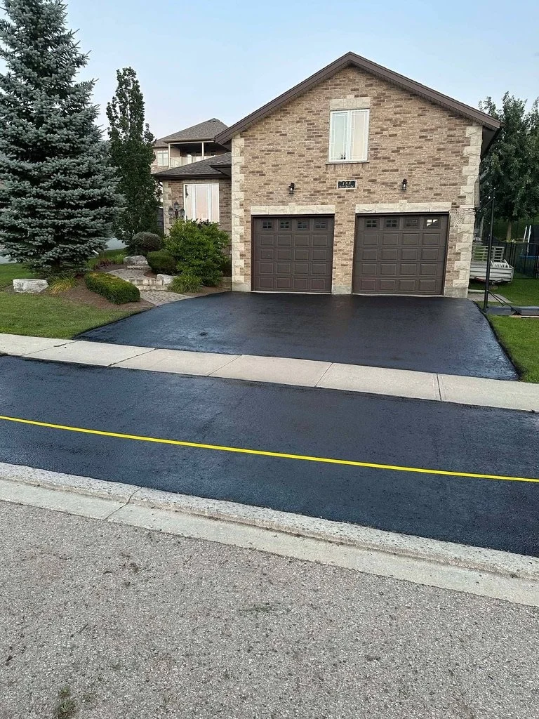 An image of a black drive way with asphalt patch and seal job with yellow caution tape at then end